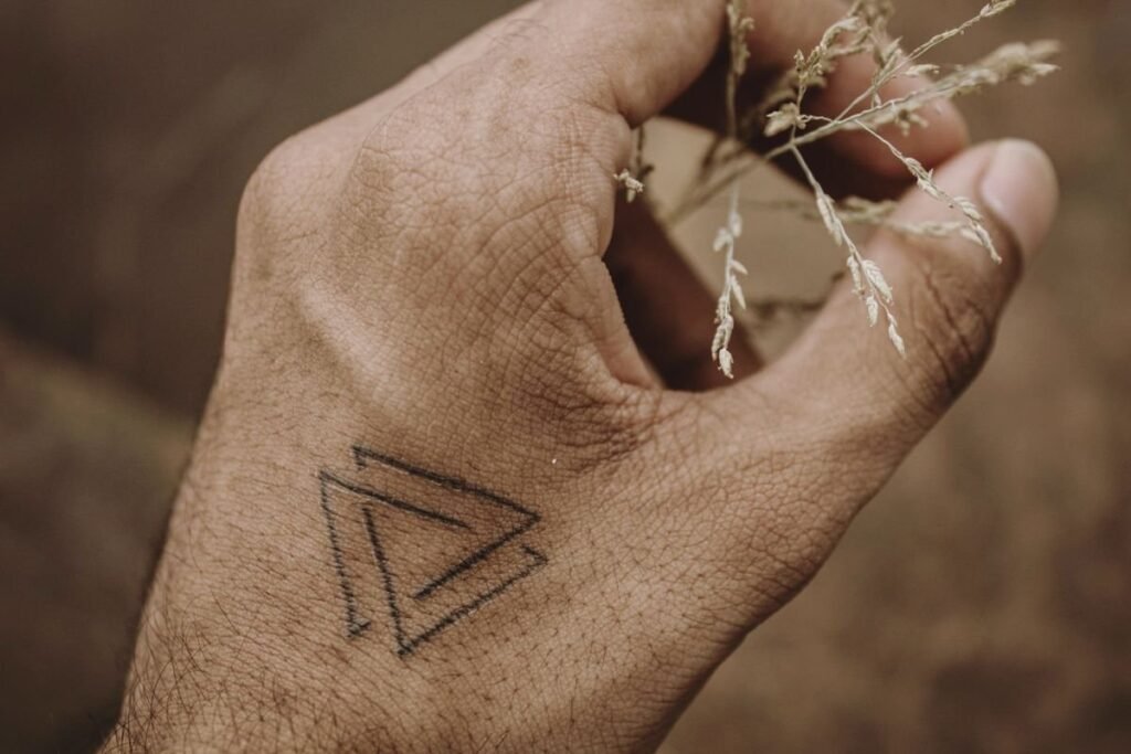 Petit triangle en tatouage minimaliste sur le dos d une main