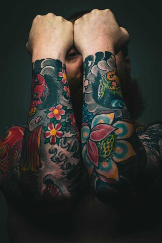 Deux avant-bras couverts de tatouages old school en couleur avec des fleurs et des carpes koi